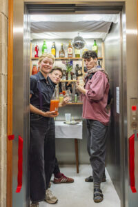 Drei Personen stehen in dem als Bar eingerichteten neuen Lift.